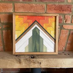 a painting on a wooden shelf in front of a brick wall with a wood frame