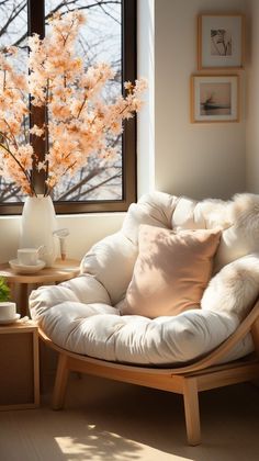 a white chair sitting in front of a window next to a vase filled with flowers