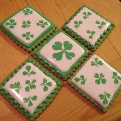 four green and white decorated cookies sitting on top of a wooden table