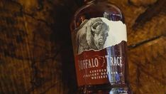 a bottle of buffalo trace whiskey sitting on top of a wooden table next to a wall