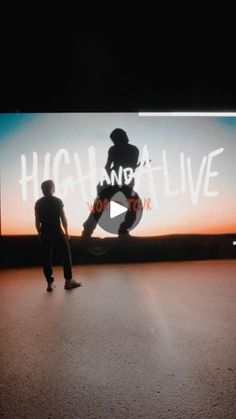 two people standing in front of a large screen with the words high and live on it