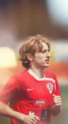 a young man in a red soccer uniform running