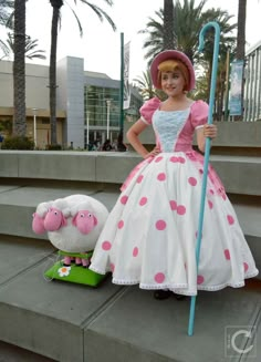 a woman in a pink and white dress standing next to a stuffed animal