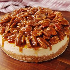 a cheesecake topped with pecans on top of a wooden table