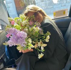 a woman sitting in the back seat of a car holding flowers