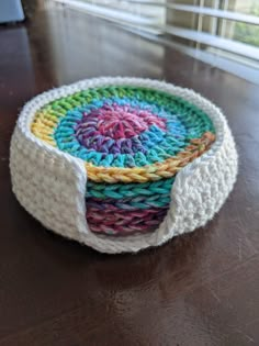 two crocheted baskets sitting on top of a wooden table next to a window