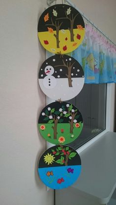 three circular magnets hanging from the side of a window with trees and snowmen on them