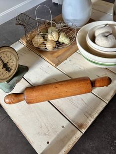 a wooden rolling pin sitting on top of a table next to other kitchen tools and knick knacks