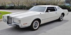 an old white car parked in a parking lot