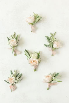 flowers arranged in the shape of a heart on a white surface with green leaves and stems