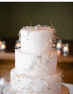 a three tiered wedding cake with pearls on it