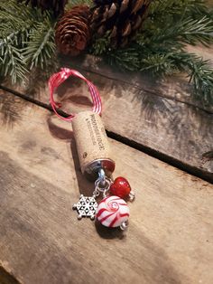 a wine bottle with a christmas ornament on it sitting next to pine cones