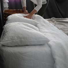 a woman placing pillows on top of a bed