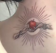 a woman's back with an apple tattoo on her shoulder and the sun shining through it