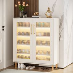 a white cabinet with glass doors and gold handles in the corner of a living room