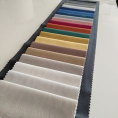 a row of different colored fabrics sitting on top of a white table next to each other