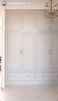 an empty room with white cabinets and chandelier