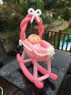 an inflatable baby's cradle on a table with a pool in the background