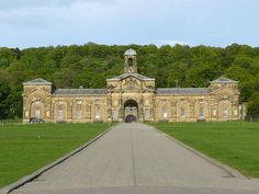 an old stone building with a clock tower on it's top and green grass in front