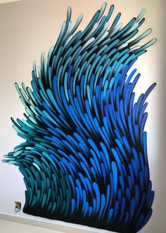 a blue and black sculpture is on display in a room with white walls that has an abstract design painted on the wall