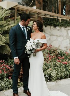 a bride and groom standing together in front of flowers