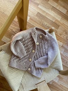 a baby sweater sitting on top of a wooden chair