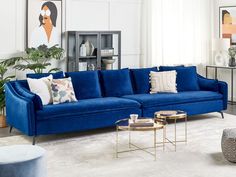 a living room filled with blue couches and pillows on top of a white rug