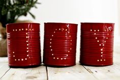 three red tin canisters sitting on top of a wooden table with the words make your own candle holders