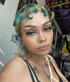 a woman with bright blue hair and piercings on her face is posing for the camera