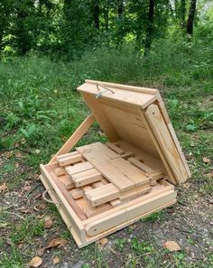 an open wooden box sitting on the ground in front of some grass and trees,