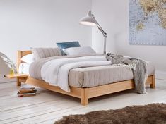 a bed with a wooden frame and headboard in a room next to a rug