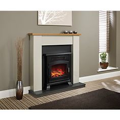 a fireplace with a fire burning in it next to a brown rug and window sill