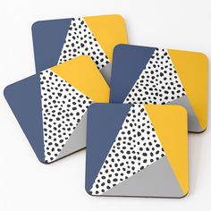 four coasters with yellow, blue and white designs on them sitting next to each other