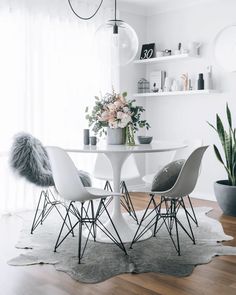 a white table with four chairs and a potted plant in the corner next to it