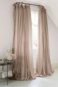 the curtains are hanging in front of a window with white walls and windowsills