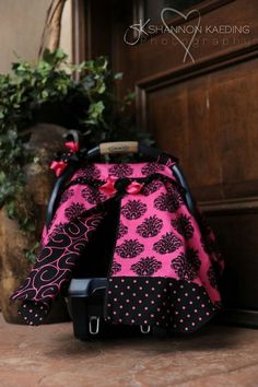 a pink and black purse sitting on top of a wooden floor next to a potted plant