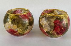 two gold and red vases sitting next to each other on a white table top