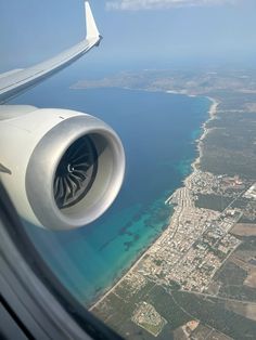 an airplane wing flying over the ocean and land