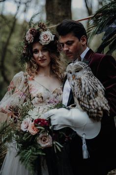 a bride and groom holding an owl in their arms while standing next to each other