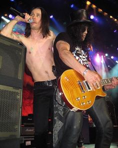 two shirtless men on stage with guitars