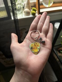 a hand holding a keychain with an image of a cat and flower on it