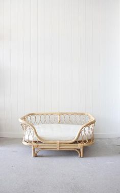 a wicker couch sitting on top of a floor next to a white wall in a room