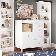 a white cabinet with drawers and a teddy bear on top in a living room area