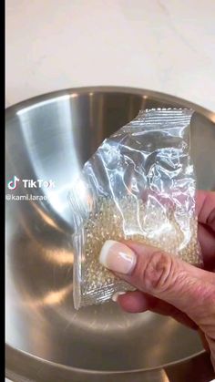 a person holding a bag of food in front of a metal bowl on a counter