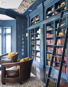 a living room filled with furniture and bookshelves next to a ladder leading up to a window