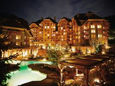 the hotel is lit up at night with lights shining on it's facade and surrounding buildings