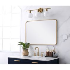 a bathroom vanity with marble counter top and brass fixtures, along with a gold framed mirror