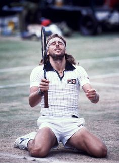 a man sitting on the ground holding a tennis racquet in his right hand