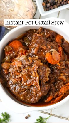 a white bowl filled with meat and carrots on top of a table next to other dishes