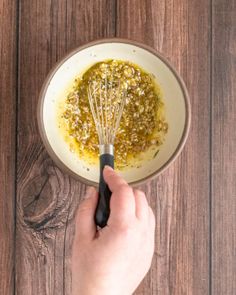 someone is whisking ingredients in a bowl on a wooden table, top view from above